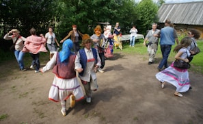 A lively group of dancers performing line dance outdoors in bright traditional attire