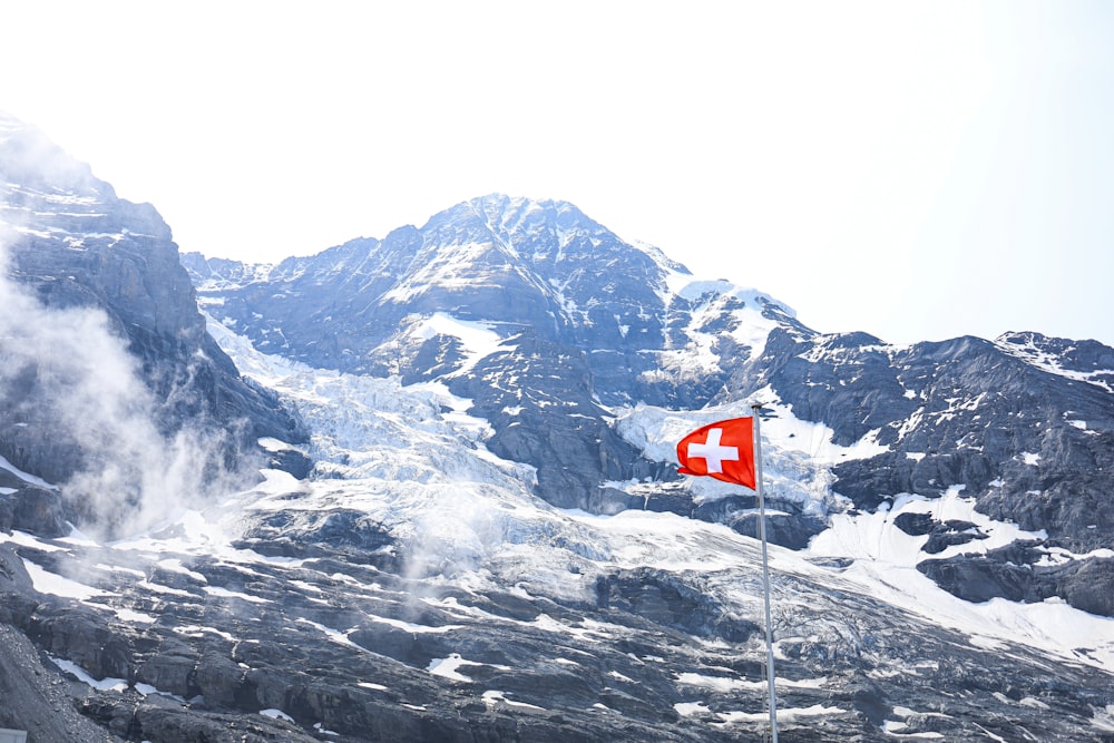 a swiss flag flying on top of a mountain
