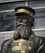 A statue of a man wearing a military uniform with a hat. The uniform is decorated with medals and has a prominent texture, colored in shades of black and gold. The background shows a modern building with large windows.