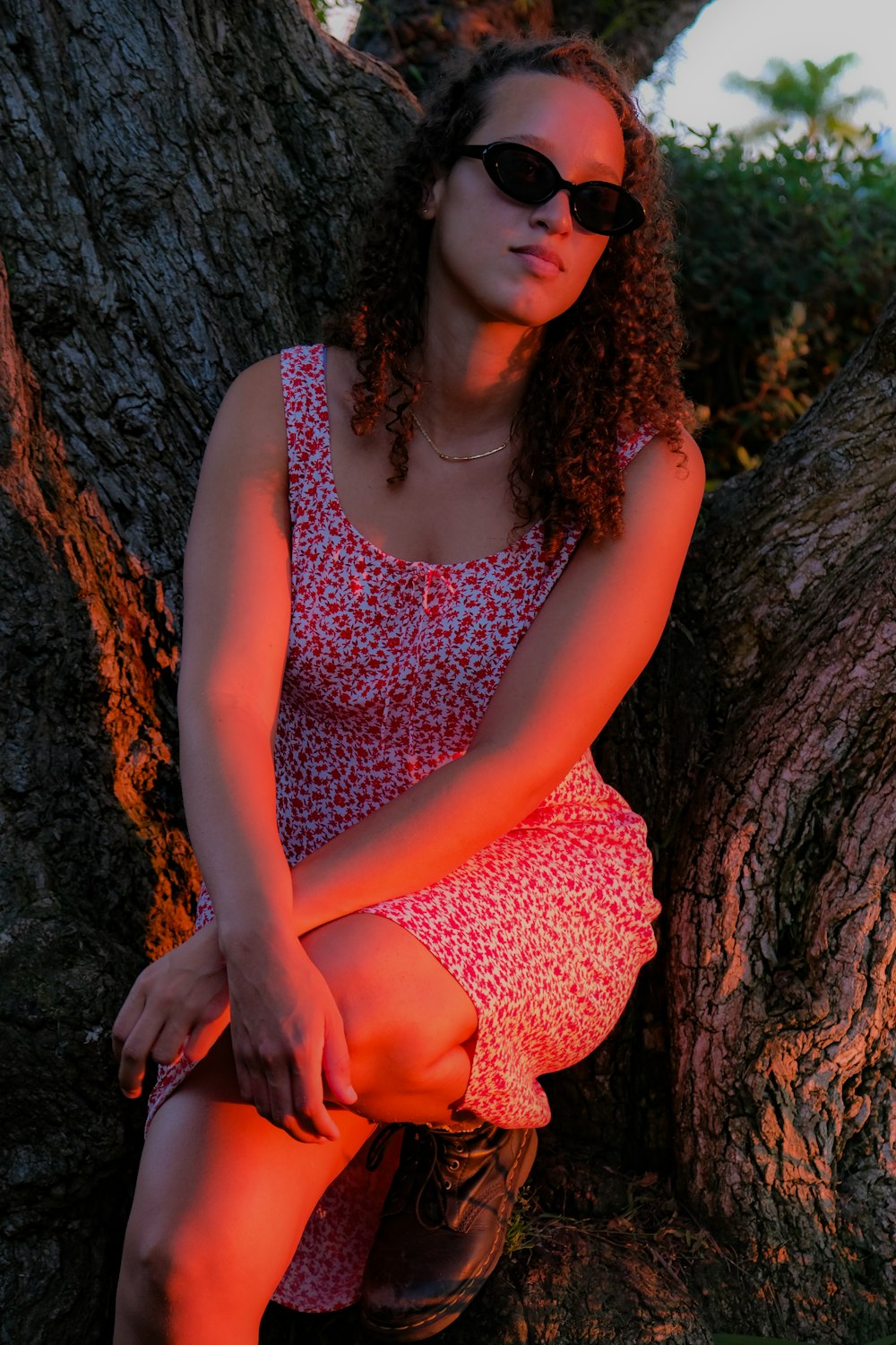 a woman wearing sunglasses sitting on a tree branch