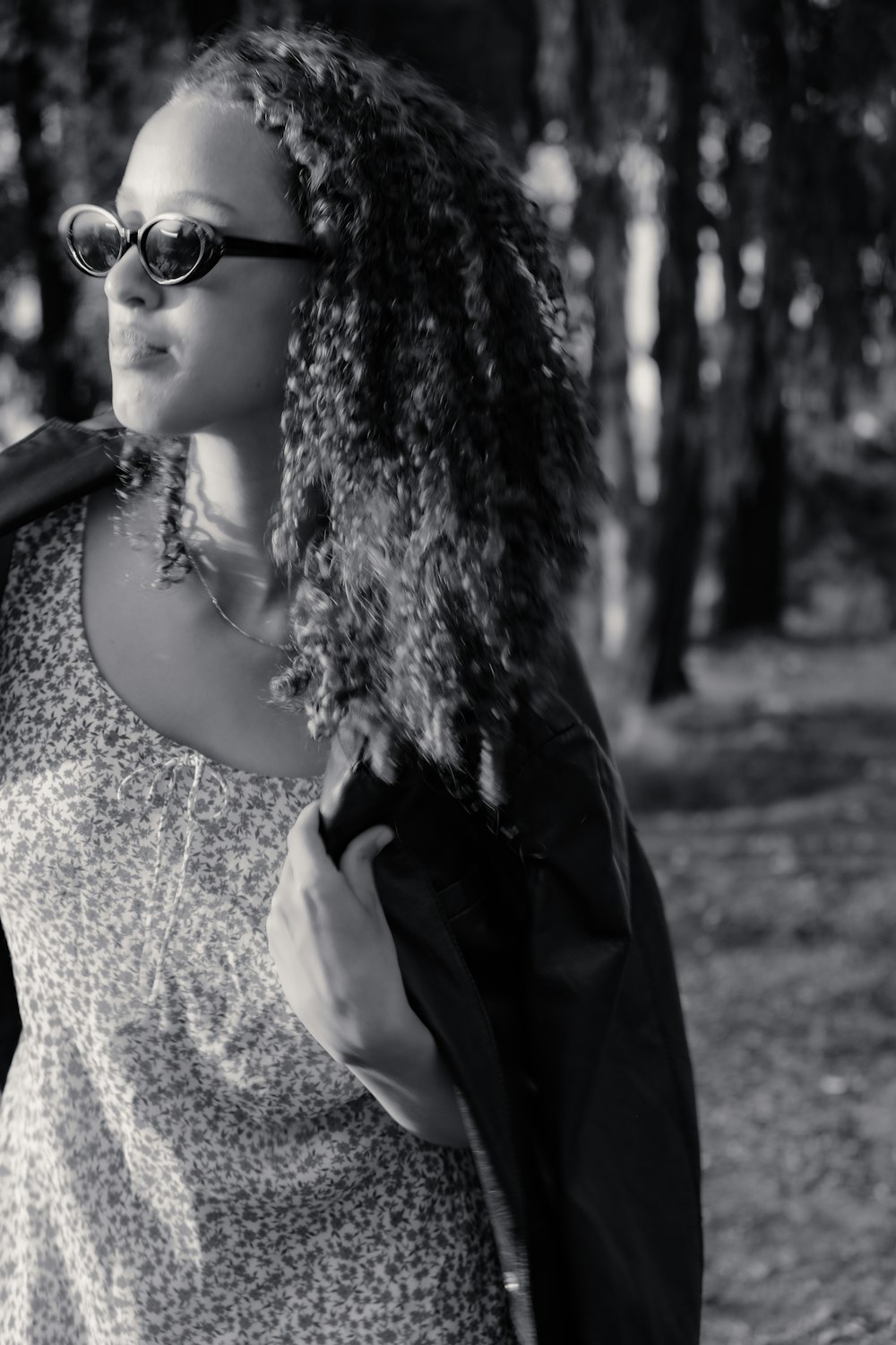 a woman wearing sunglasses and a jacket in the woods