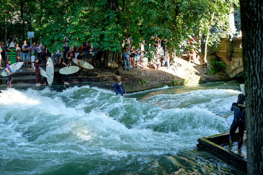 a group of people standing around a river with surfboards
