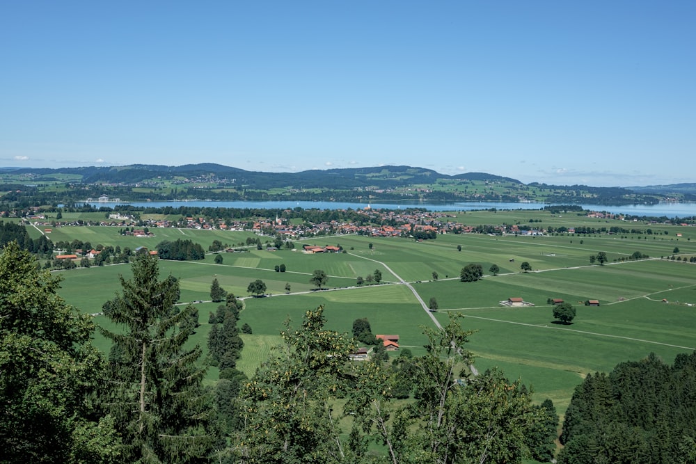 Una vista panorámica de un valle verde con un lago en la distancia