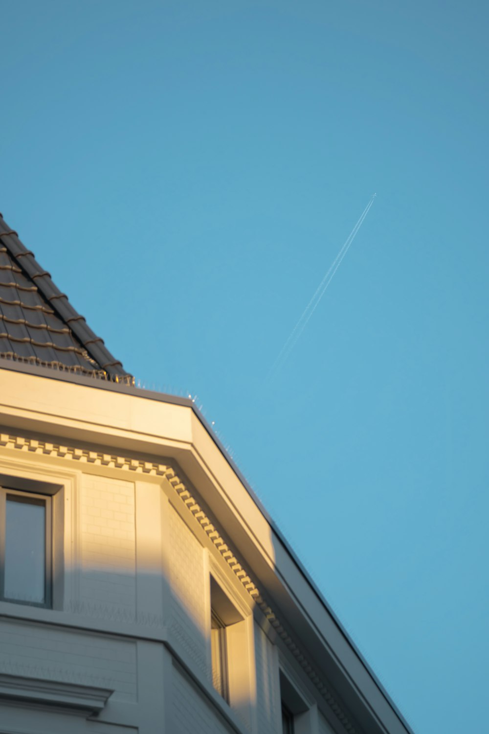 an airplane is flying over a house at dusk