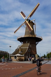 a man riding a bike past a windmill