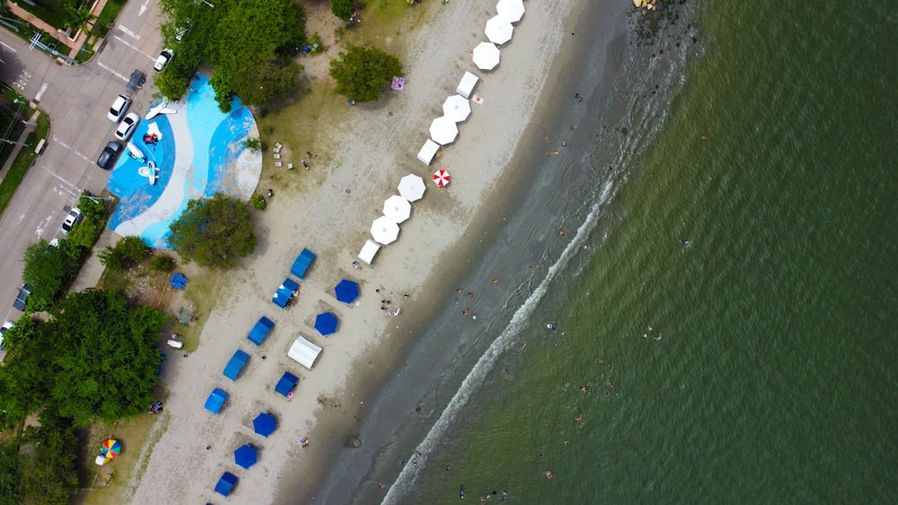 an aerial view of a beach with blue and white umbrellas