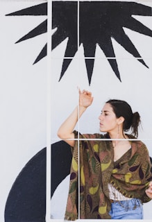 A woman posing in front of a colorful mural, wearing trendy accessories.