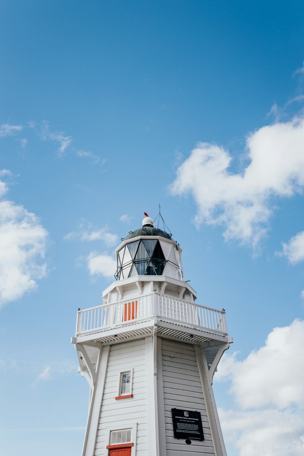 Un faro bianco con una porta rossa in una giornata di sole