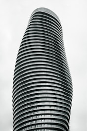 A tall, modern skyscraper with a unique, twisting architectural design composed of horizontal stripes. The building has a sleek and futuristic appearance, with numerous floors and windows.
