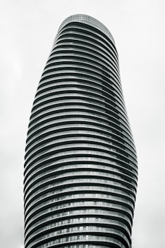 A tall, modern skyscraper with a unique, twisting architectural design composed of horizontal stripes. The building has a sleek and futuristic appearance, with numerous floors and windows.