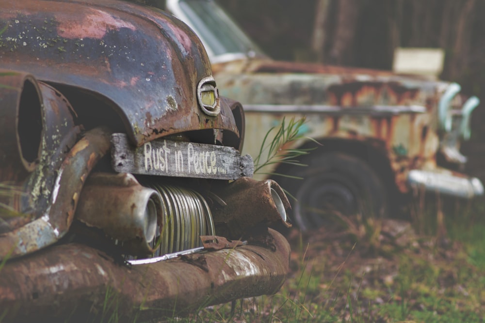 an old rusted car sitting in the grass