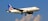 A commercial airplane with the United Airlines logo is flying against a backdrop of a clear blue sky with some clouds. The aircraft is white with blue and gold accents, and its wings are spread wide.