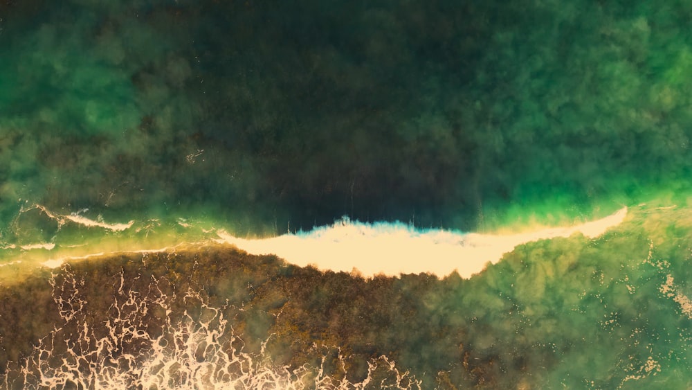 an aerial view of a wave breaking on a beach