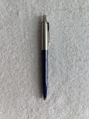 Close-up of a ballpoint pen with a polished chrome finish resting on a sheet of paper.
