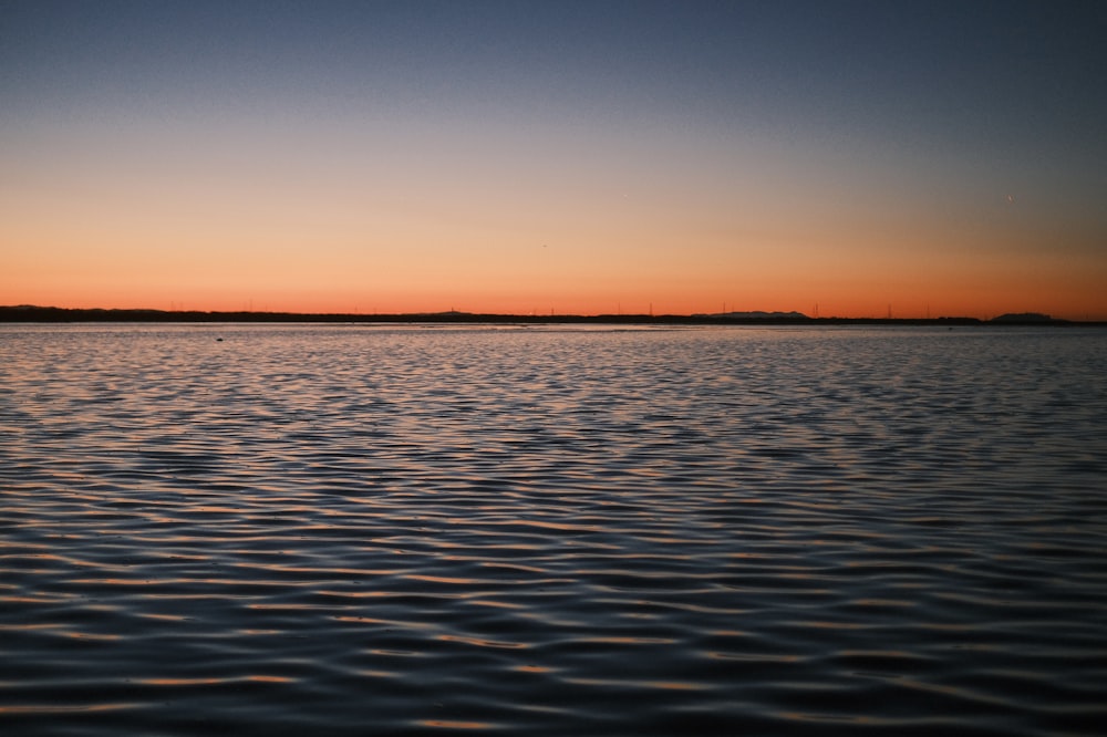 a body of water with a sunset in the background