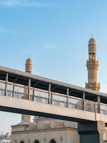 a bridge over a body of water with a clock tower in the background