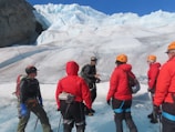 Guide demonstrating rope techniques to attentive climbers on a glacier.