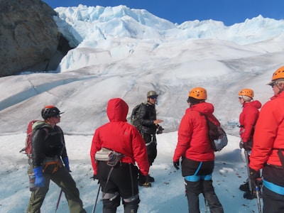 Guide demonstrating rope techniques to attentive climbers on a glacier.