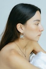 a woman in a white dress wearing a pair of earrings