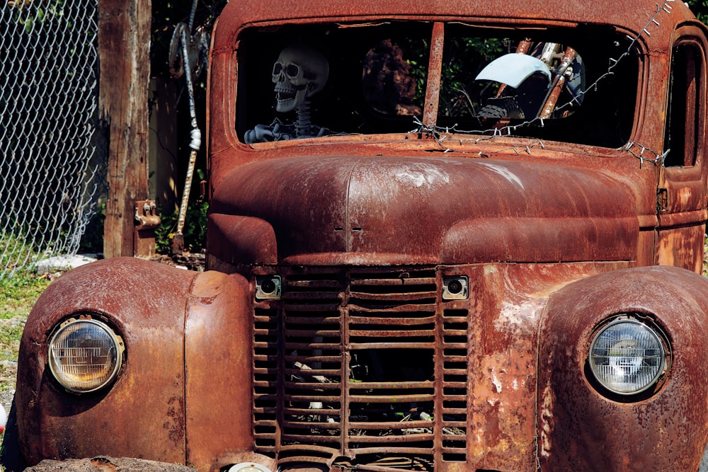 an old rusted truck with a skeleton on the front