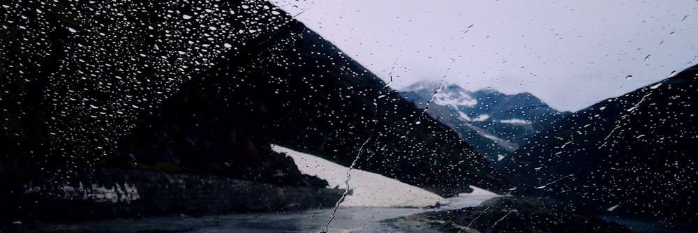 a view of a mountain range through a rain soaked window