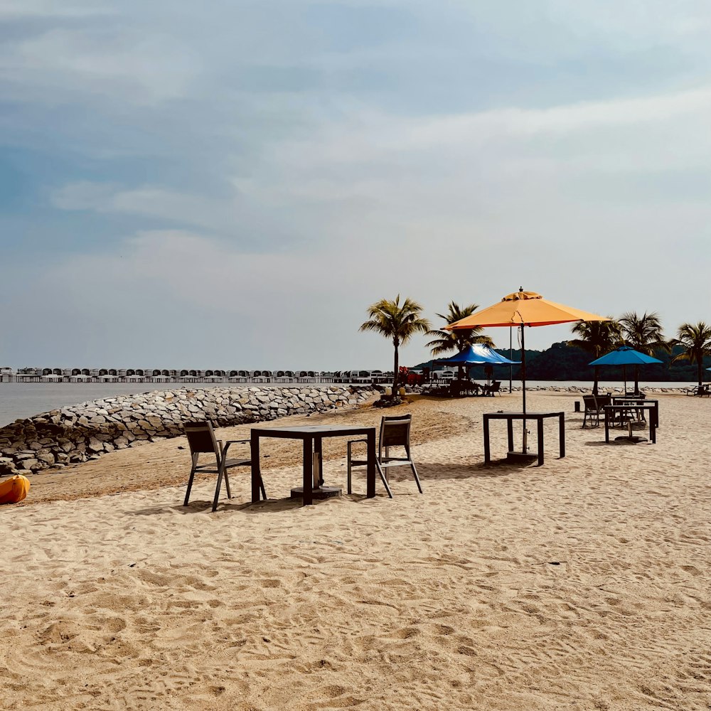 a sandy beach with tables and umbrellas on it