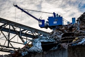 Steel scrap being weighed on an industrial scale with inspectors overseeing the process.