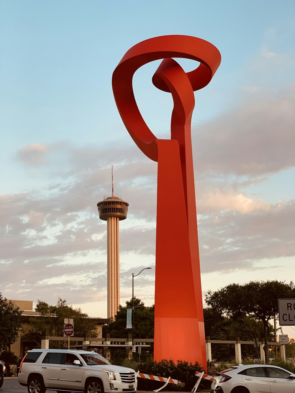 a large red sculpture in the middle of a parking lot