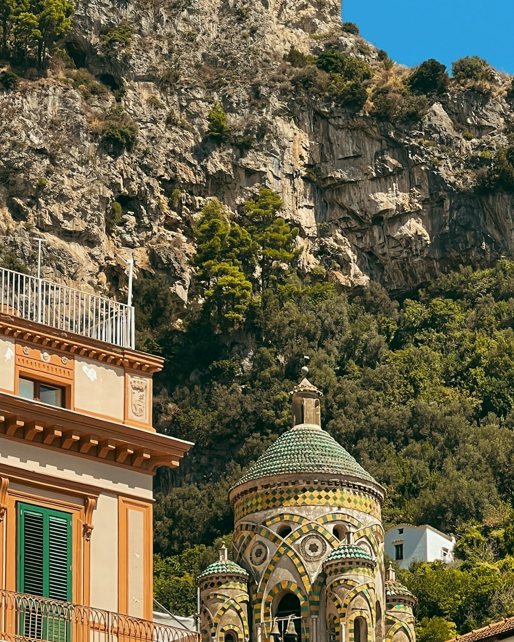 a building in front of a mountain with a clock on it