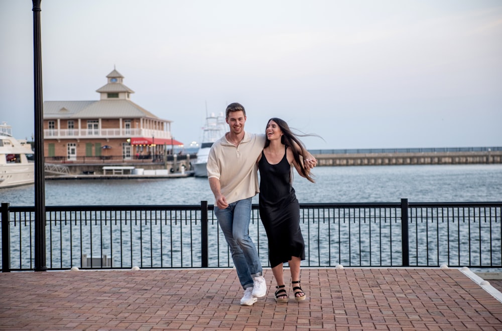 a man and a woman are walking by the water