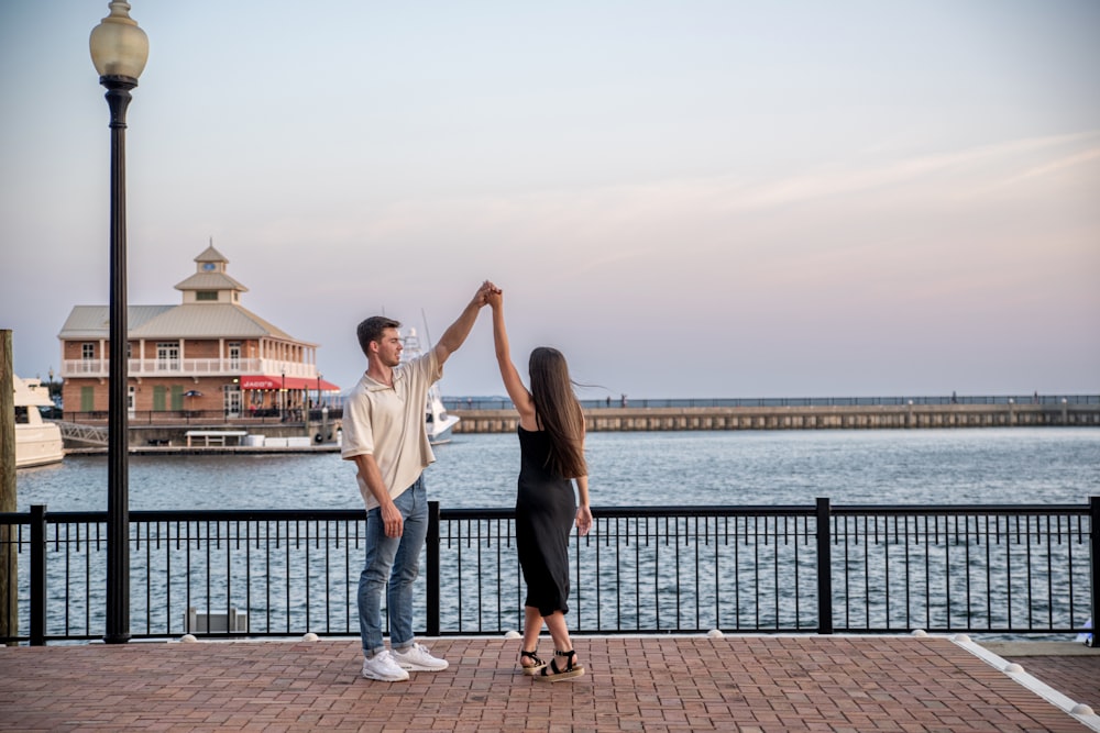 a man and a woman holding hands near a body of water