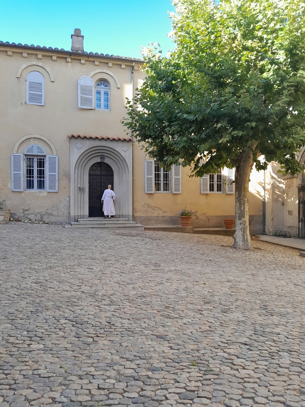 a woman in a white dress standing in front of a building