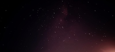 A vibrant night sky filled with stars and subtle zodiac constellation lines glowing softly.