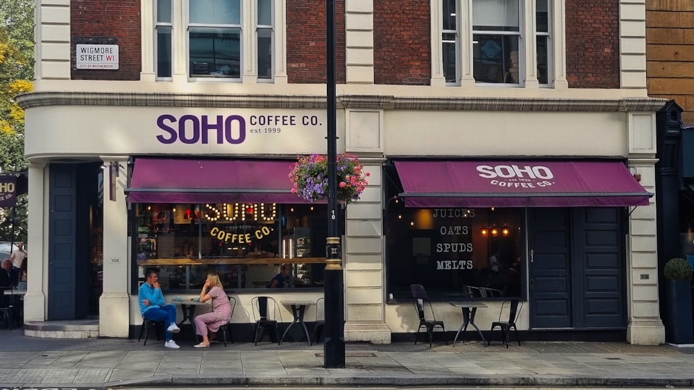 a couple of people sitting outside of a coffee shop