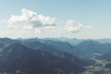 Panoramic view of lush green valleys framed by the sharp summits of Panchachuli under a bright blue sky.