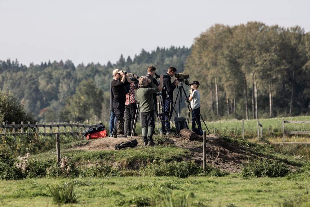 a group of people standing on top of a lush green field