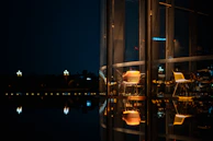 A cinematic view of a city café at dusk, warm lights glowing inside against a cool twilight sky.