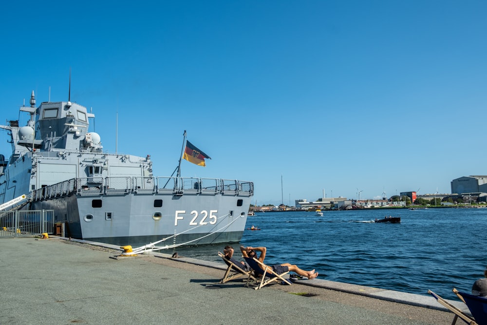 a large boat docked at a pier with people sitting on chairs