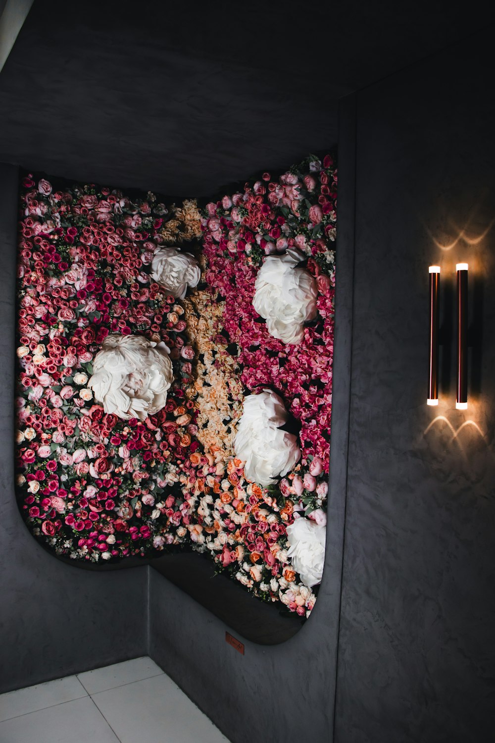 a black wall with flowers and lights on it