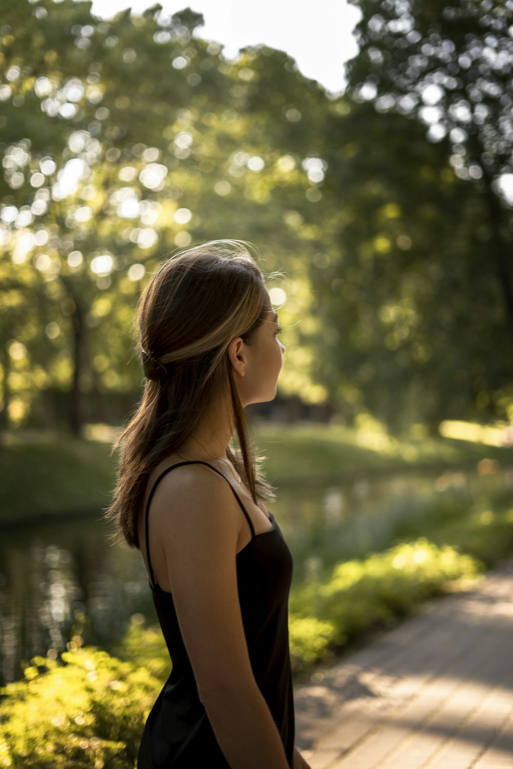 a woman standing on a wooden walkway next to a lake