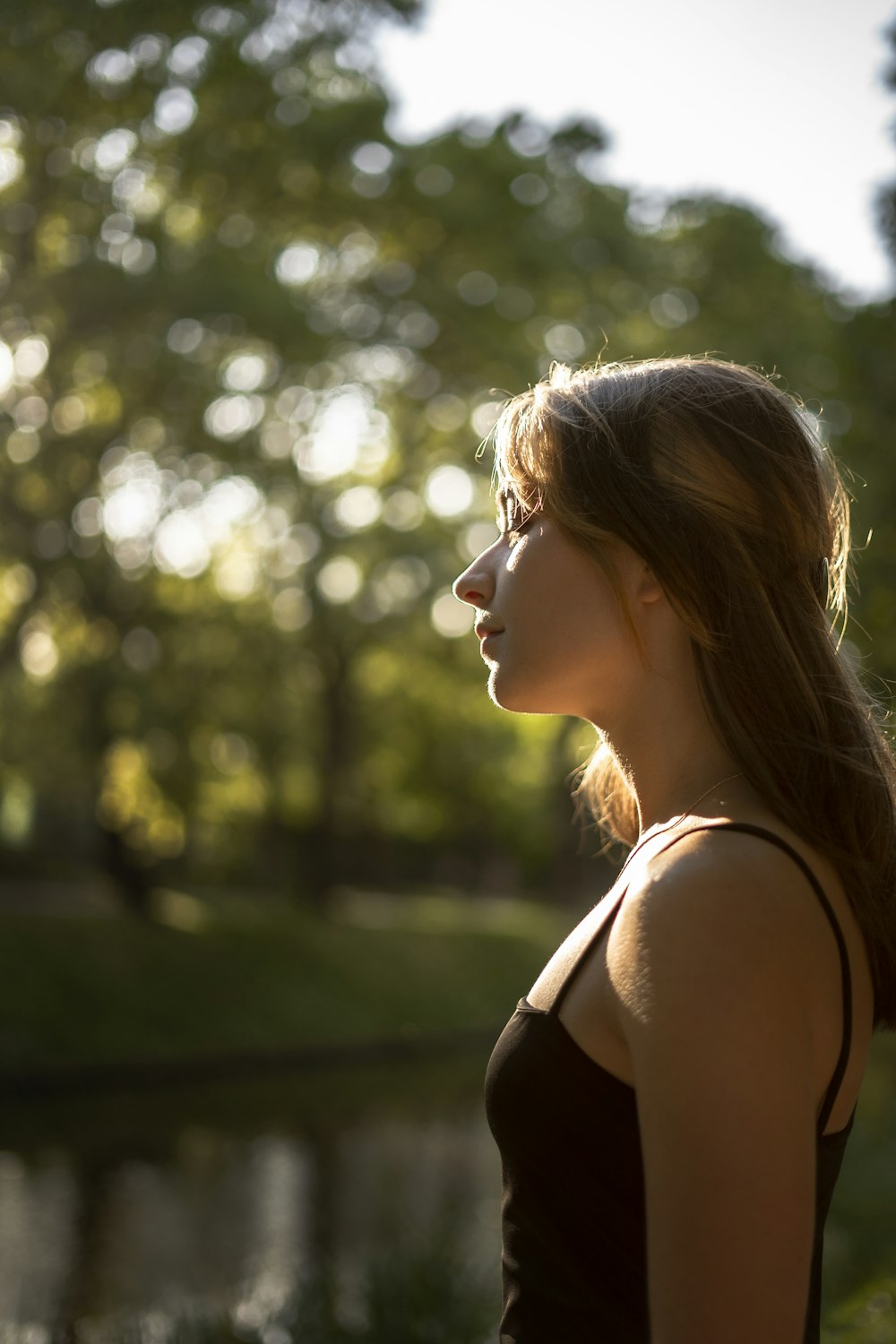 a woman standing in front of a lake with trees in the background