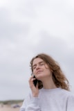 a woman standing on the beach talking on a cell phone