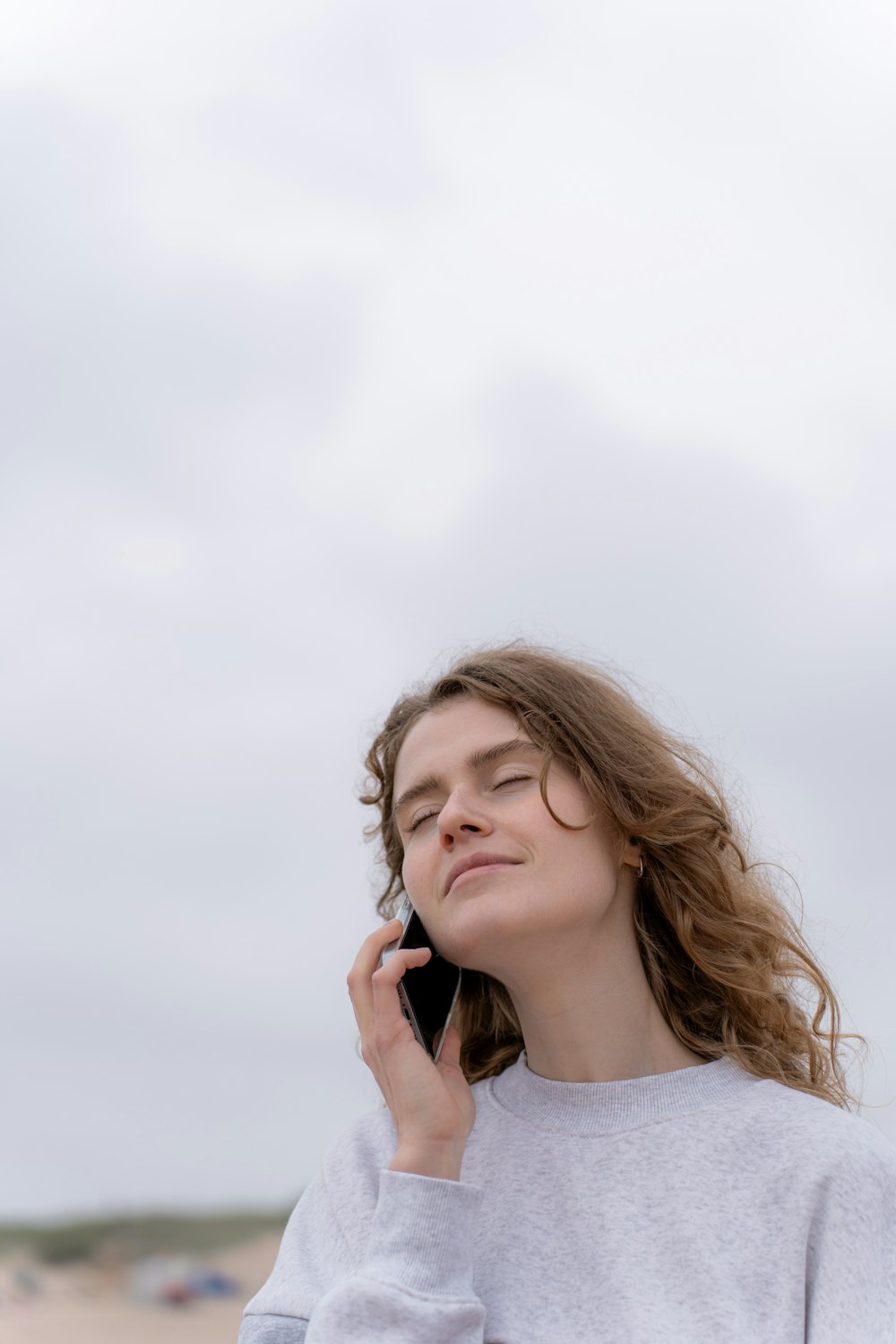 a woman standing on the beach talking on a cell phone