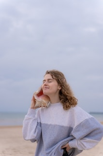 a woman standing on a beach holding a seashell