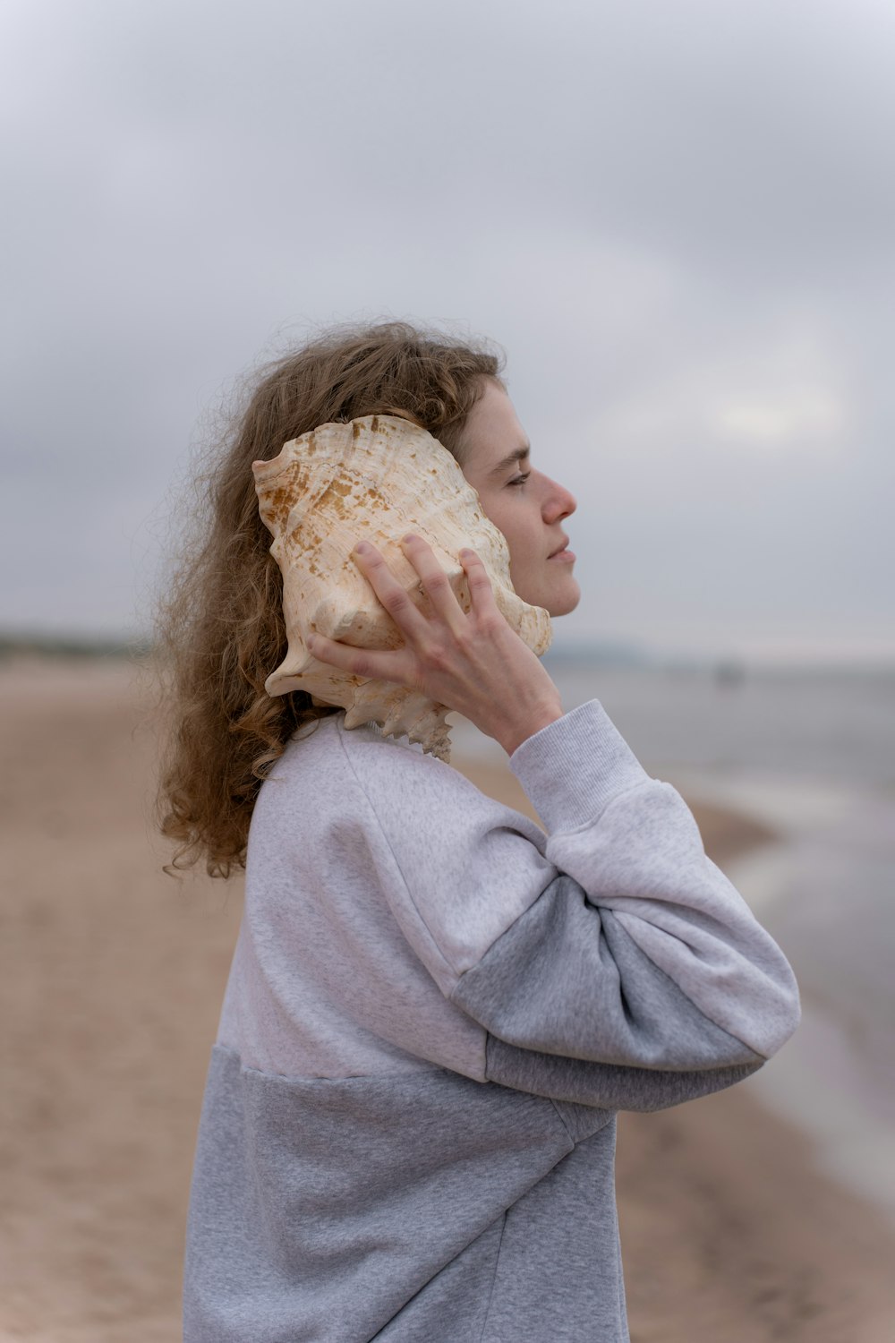 a woman holding a seashell up to her face