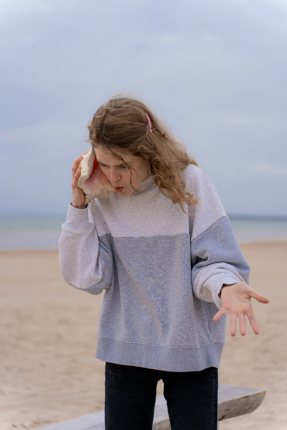 a woman standing on a beach holding a hot dog