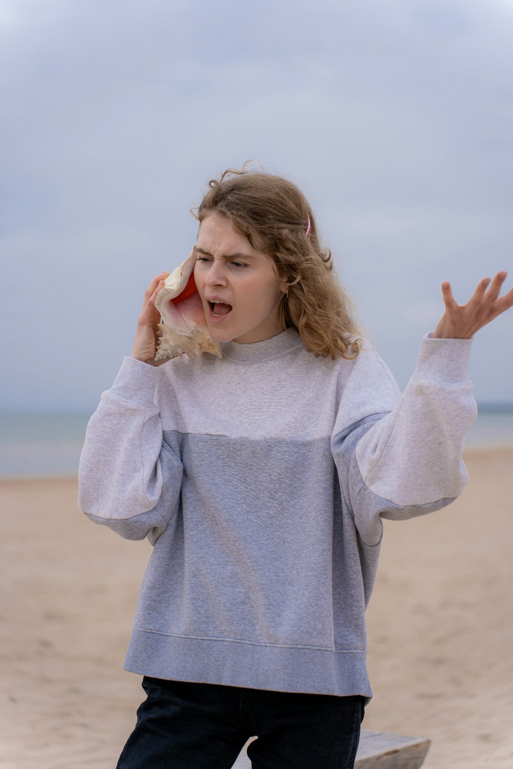 uma mulher na praia segurando um celular no ouvido