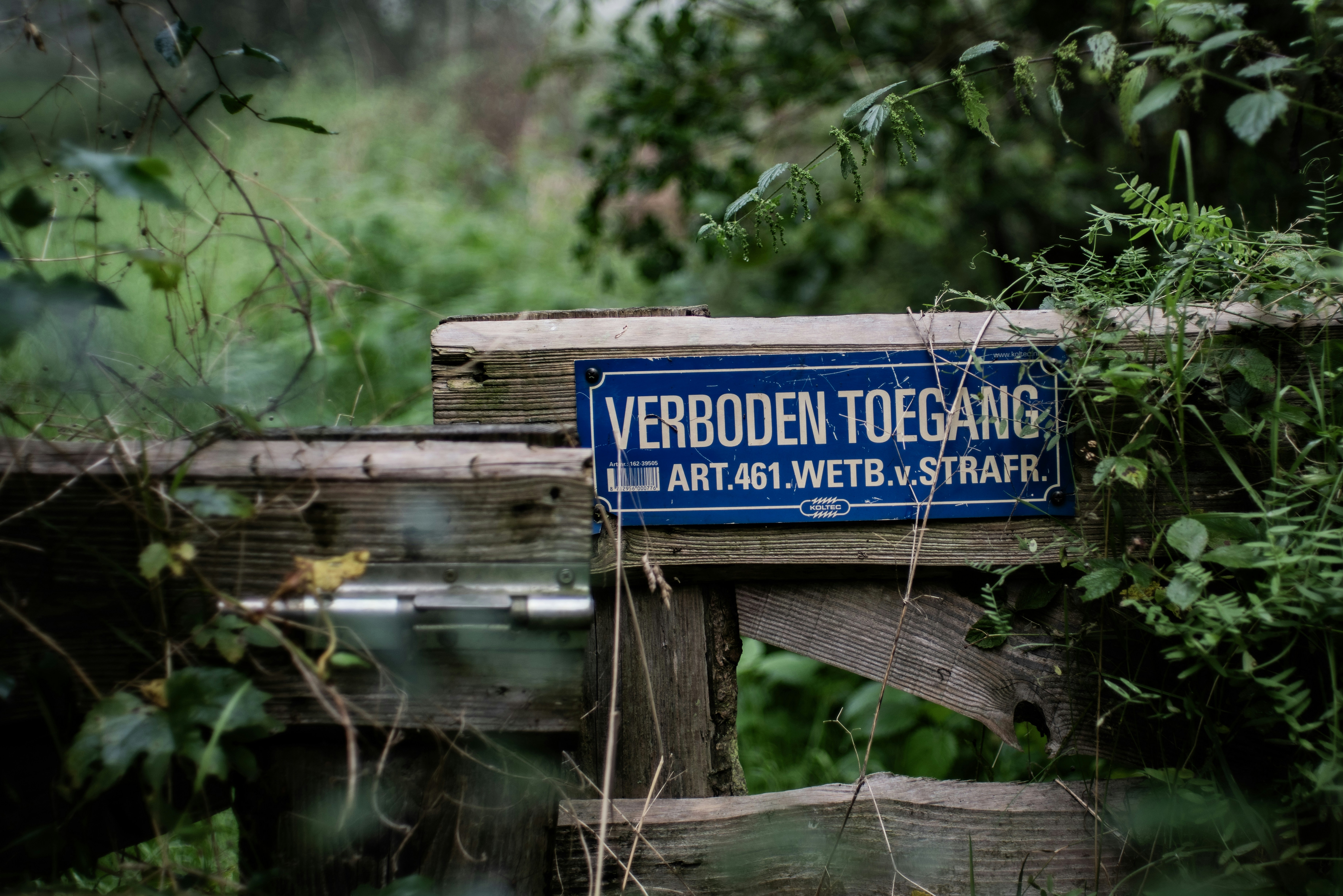a blue street sign sitting on top of a wooden fence
