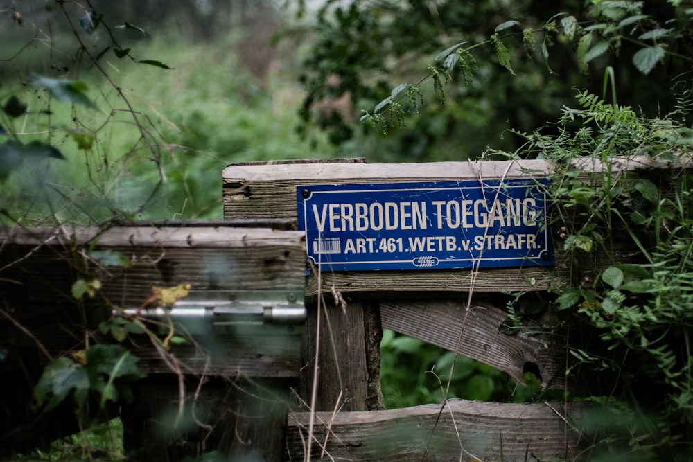 a blue street sign sitting on top of a wooden fence