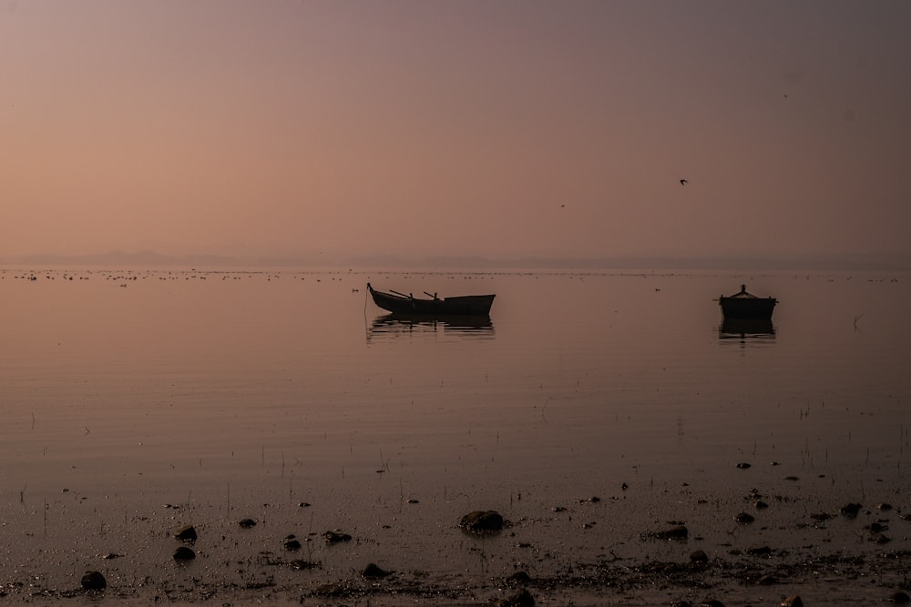 a couple of boats floating on top of a lake